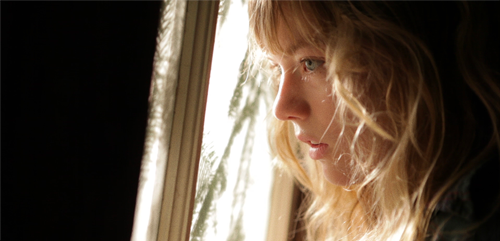 Image of a young woman looking dramatically out a window