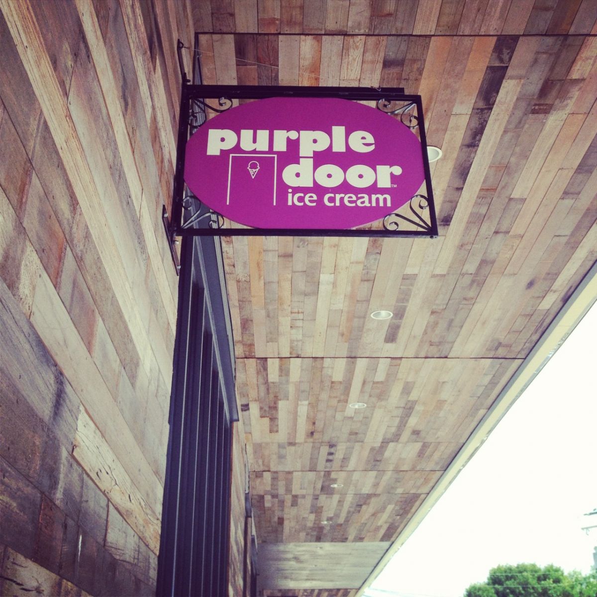 Image of a sign reading purple door ice cream hangs above the entrance